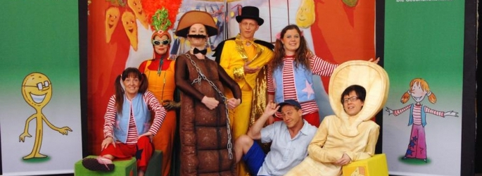 Theatergruppe in lustigen, kinderfreundlichen Kostümen auf der Bühne