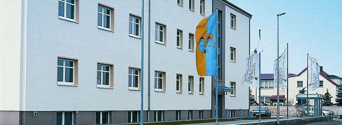 Gebäude der Stadtwerke Haldensleben in der Straßenansicht mit Flaggenmasten davor