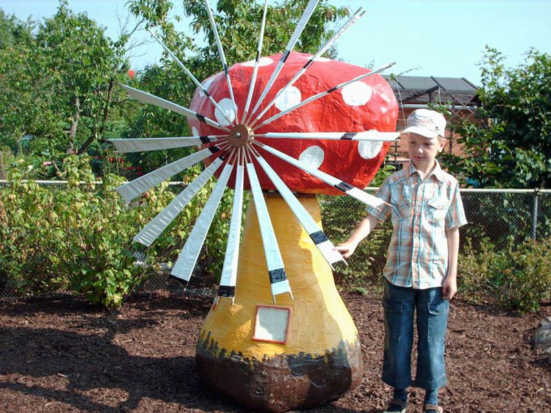 Kleiner Junge vor einer lebensgroßen Fliegenpilz-Windmühle