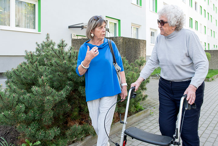 Eine Seniorin unterhält sich mit einer Frau während eines Spaziergangs.