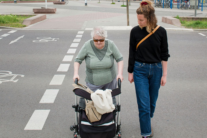 Eine Frau und Seniorin überqueren gemeinsam die Straße.