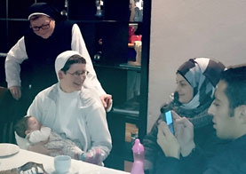 Nonnen im Gespräch mit junger Flüchtlingsfamilie