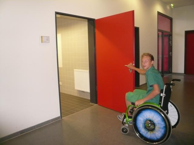 Schüler in einem Rollstuhl öfnet eine Tür