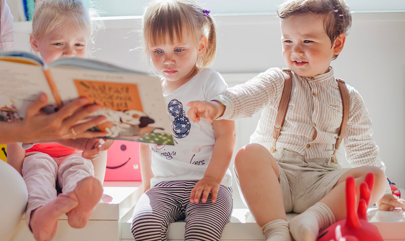 Drei Kleinkinder schauen in ein Buch
